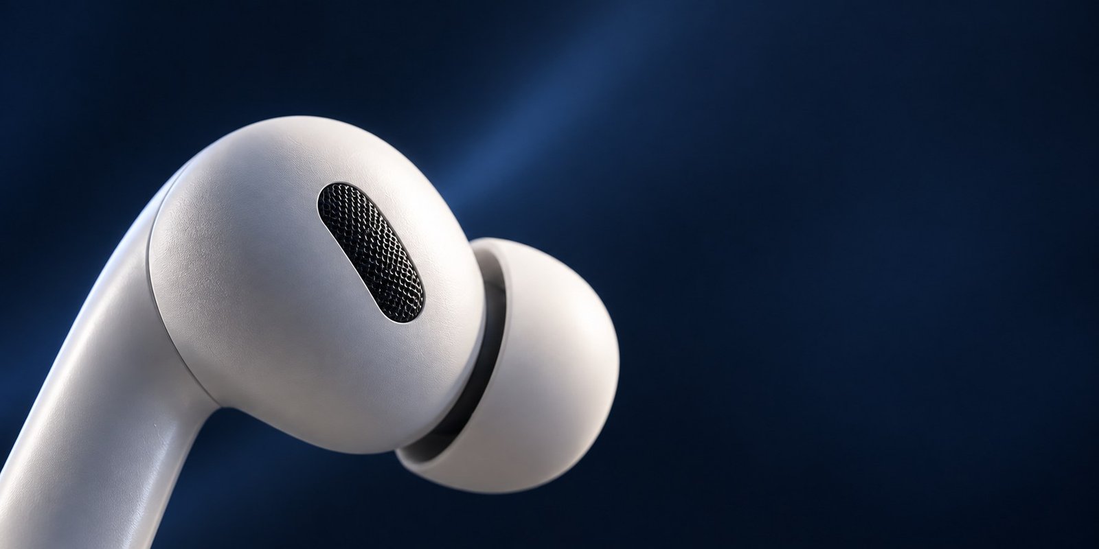 Close view of a white wireless earbud against a deep navy background